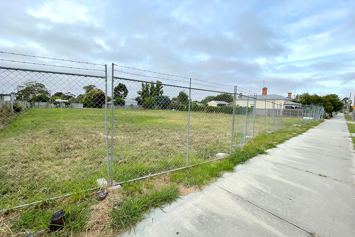 Description: Photo of a vacant residential block with temporary fence erected at the footpath. AS Planning are Town Planners in Victoria.